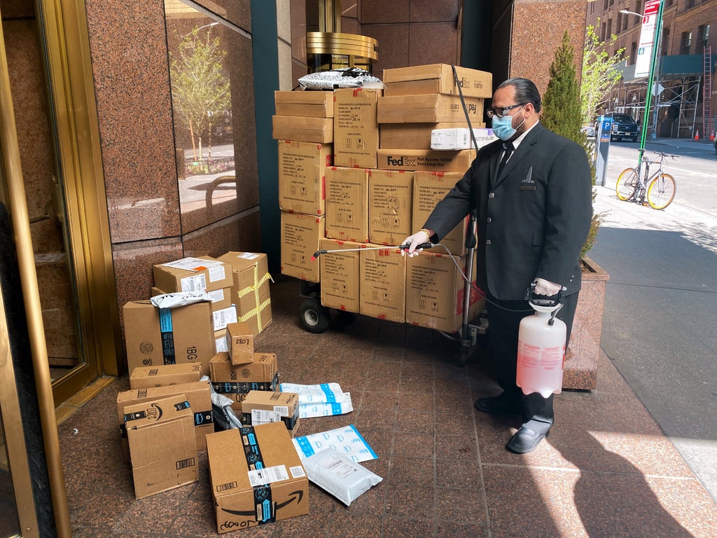 At CitySpire, a condominium on West 56th Street, coronavirus protocol includes spraying packages with a disinfectant before bringing them inside.Credit...